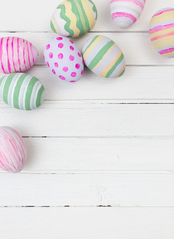 50099695 – easter eggs painted in pastel colors on a white wood background